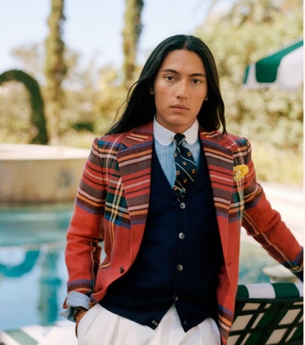 Man wears red plaid sport coat over vest and tie.