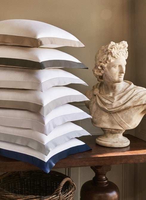 Stacked pillows next to stone bust.