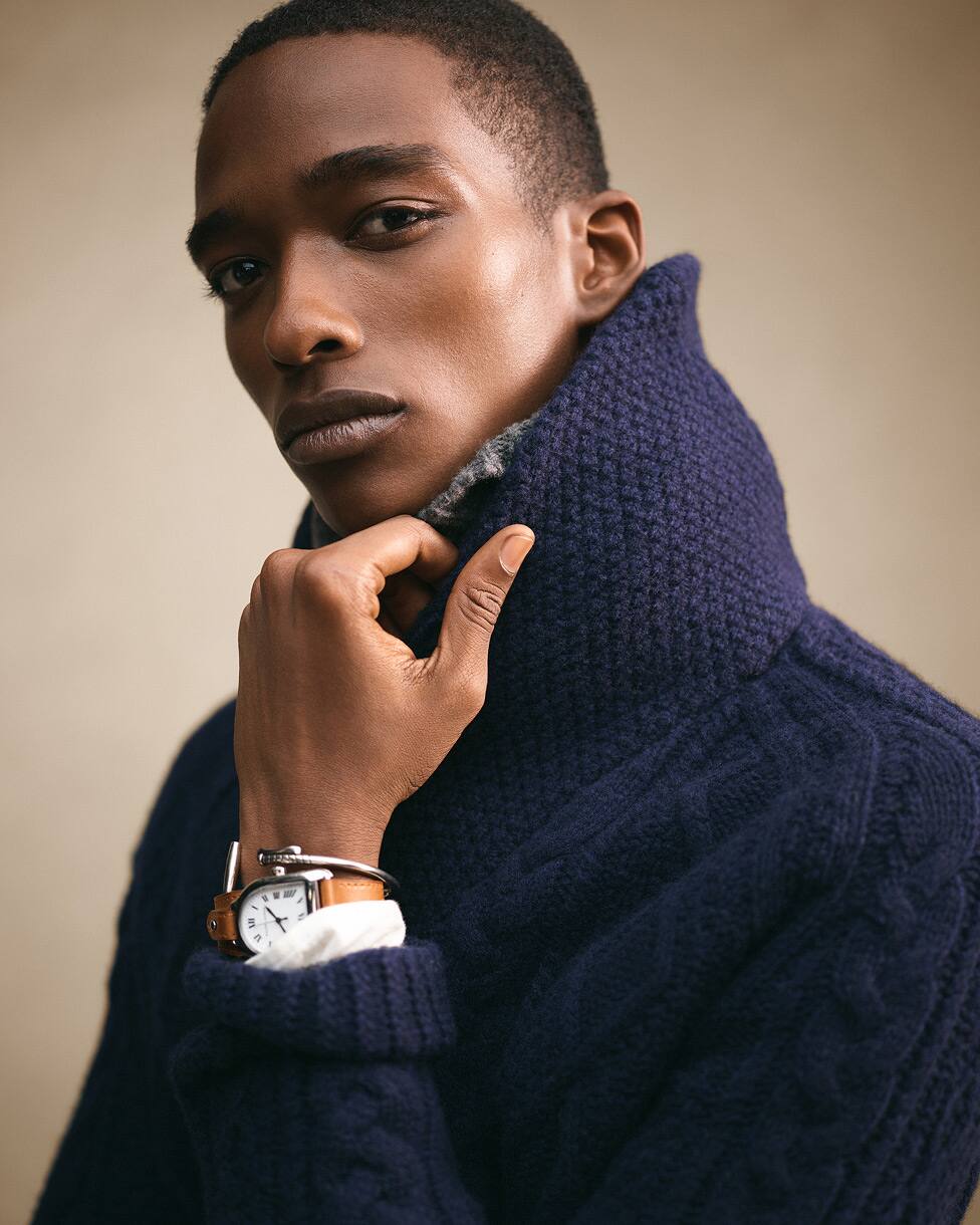 Grande plano de homem com camisola de malha trançada azul-marinho com gola alta.